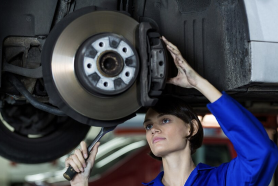 A woman performing car brake repair services.